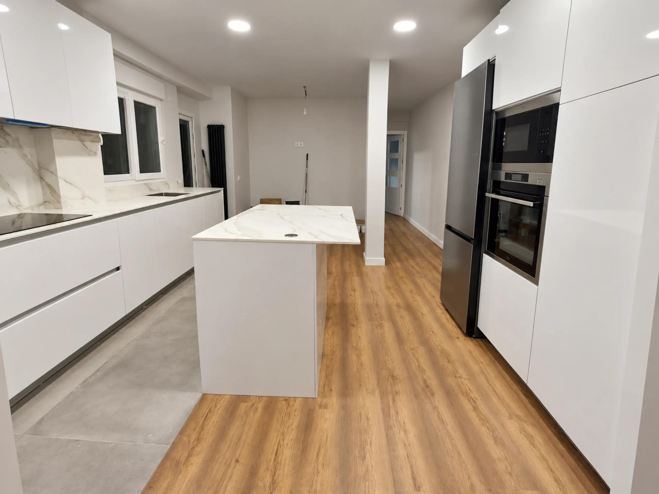 Cocina blanca con isla exenta y suelo de madera