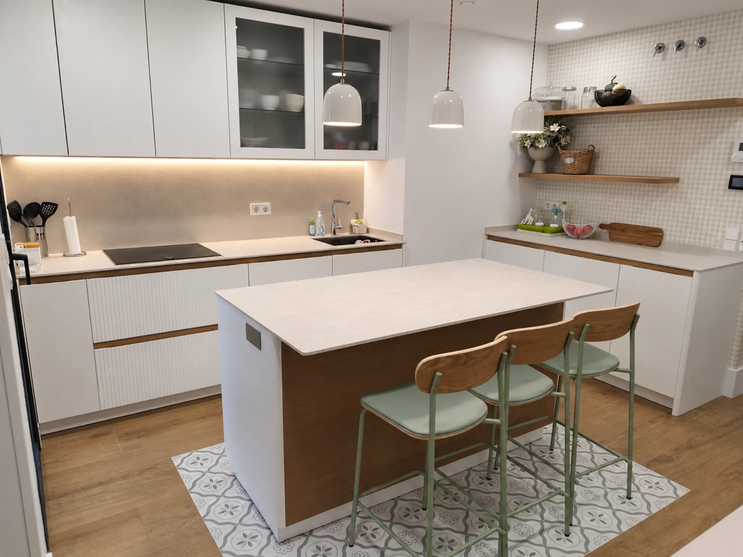 Cocina blanca con isla de lateral de madera, taburetes verdes y baldas abiertas