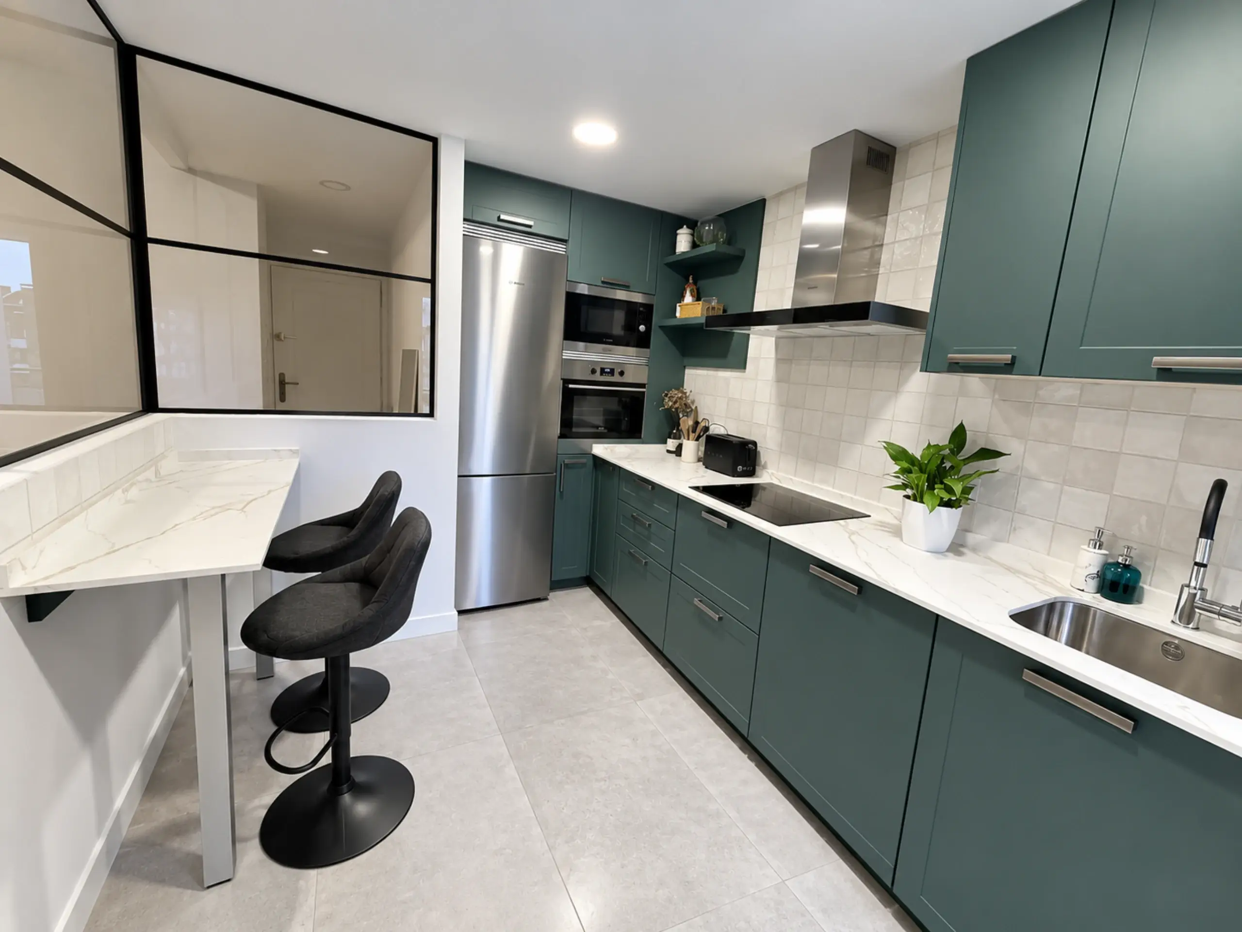 Cocina verde con barra y taburetes negros junto al cerramiento de cristal
