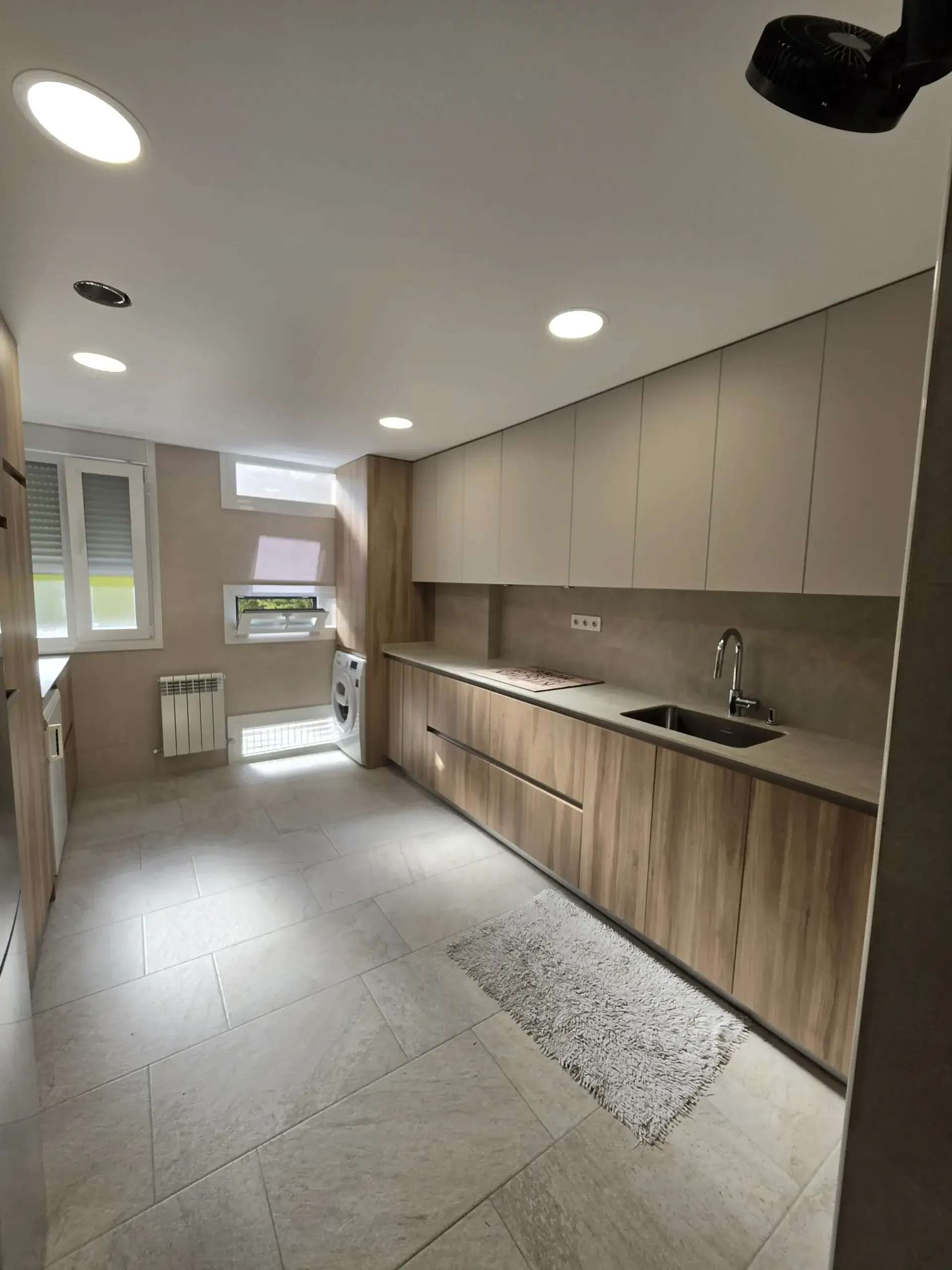 Cocina en paralelo en madera y gris claro con la ventana al fondo