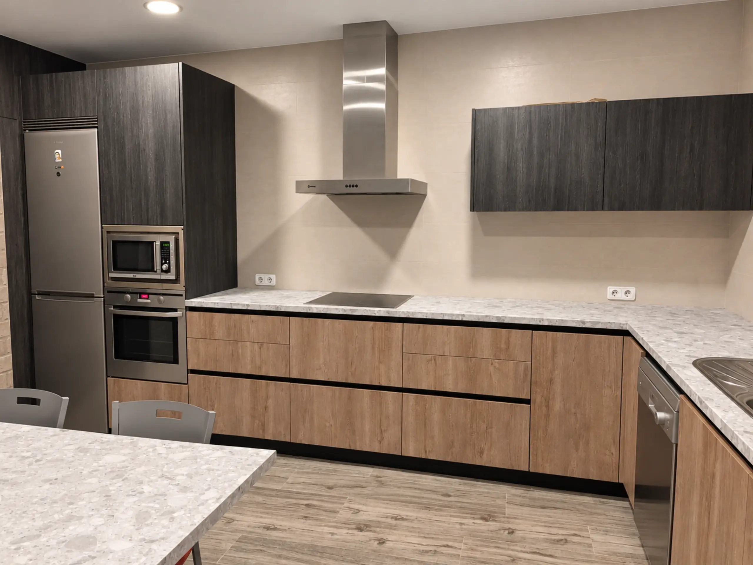 Columna oscura con frigorífico y hornos junto a la cocina en L de madera