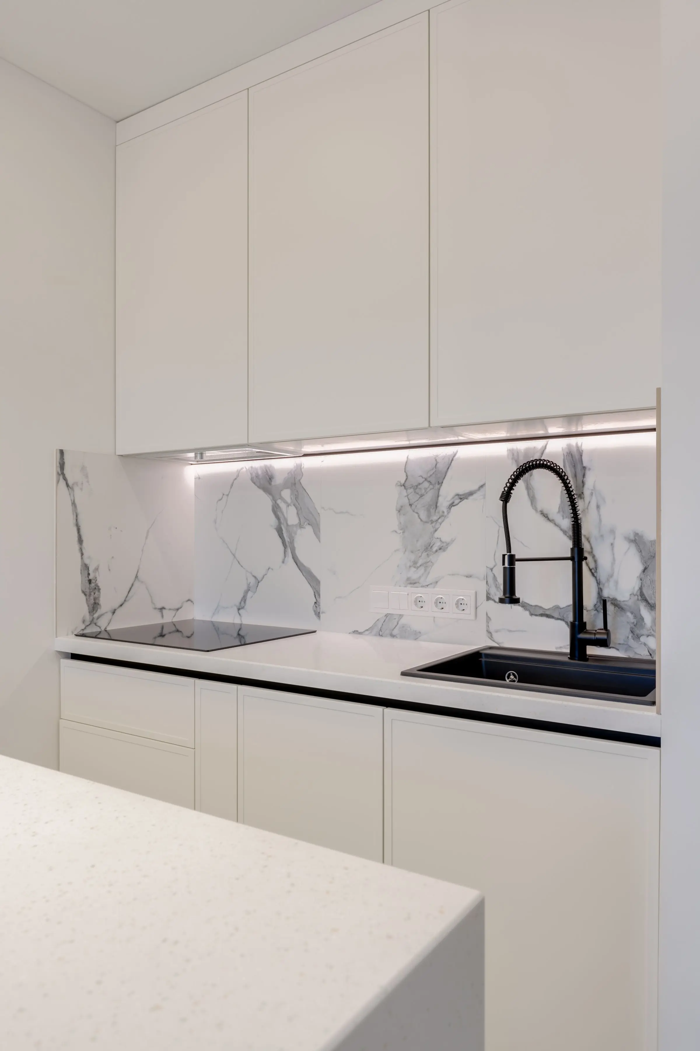 Frontal de cocina en piedra blanca de veta gris con grifo negro